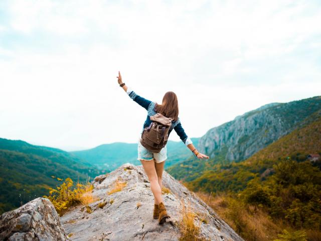 Girl on a mountain top with arms outstretched 